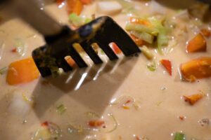 Kokosmilch und Currypulver werden in die pürierte Kürbissuppe eingerührt für eine cremige Konsistenz und würziges Aroma