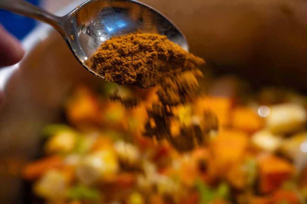 Kokosmilch und Currypulver werden in die pürierte Kürbissuppe eingerührt für eine cremige Konsistenz und würziges Aroma