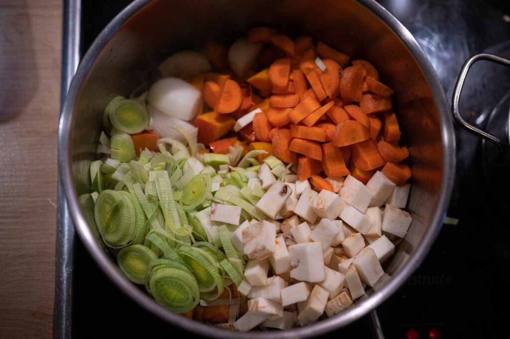 Fein geschnittene Zwiebeln werden in neutralem Öl glasig angeschwitzt – Basis für Kürbissuppe mit Kokosmilch