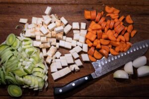 Zutaten für Kürbissuppe mit Kokosmilch – Hokkaido, Zwiebel, Curry, Brühe, Kokosmilch, Salz und Pfeffer auf Holzuntergrund