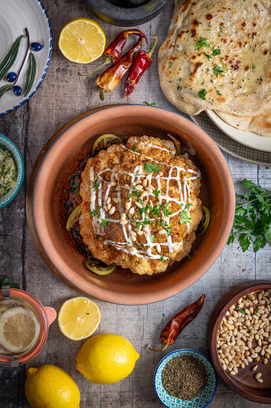 Ein Rezept für Gebackener Blumenkohl im Ofen mit orientalischen Gewürzen, zubereitet im Römertopf. Dazu gibts Petersilie und geröstete Pinienkerne und Tahinisoße.