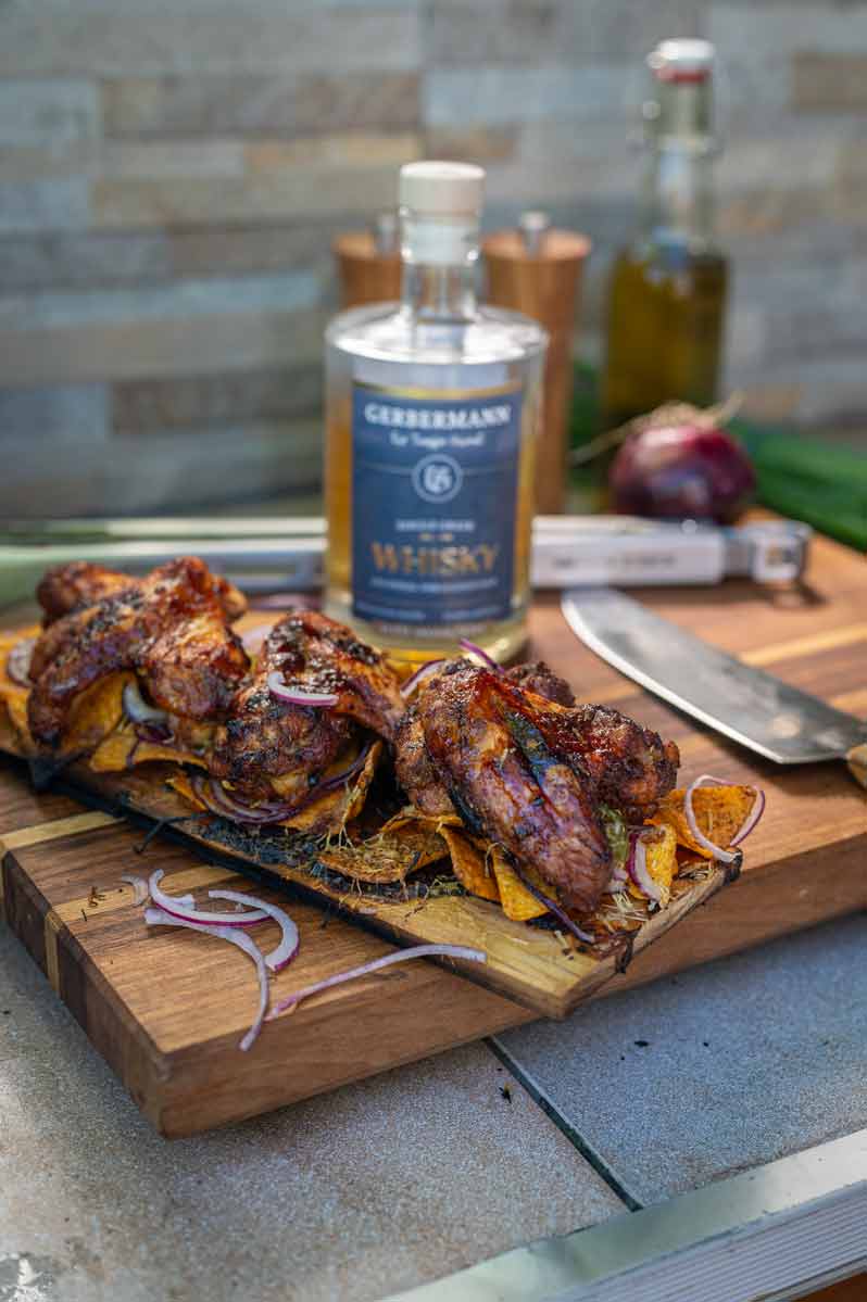 Ein Rezept für mit Whisky flambierte Chicken Wings mit Nachos, Käse und Jalapenos vom Grill