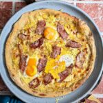 Knusprige Pizza Carbonara mit flüssigem Eigelb, Pancetta und Parmesan auf Holzbrett serviert