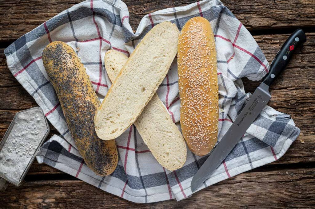 Frisch gebackene Sandwich Baguettes mit goldbrauner Kruste und einer Bestreuung aus Sesam und Mohn.