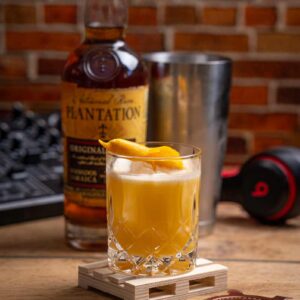 Ein erfrischender Brass Monkey Cocktail mit Wodka, Rum und Orangensaft, serviert auf Eis und garniert mit einer Orangenzeste.