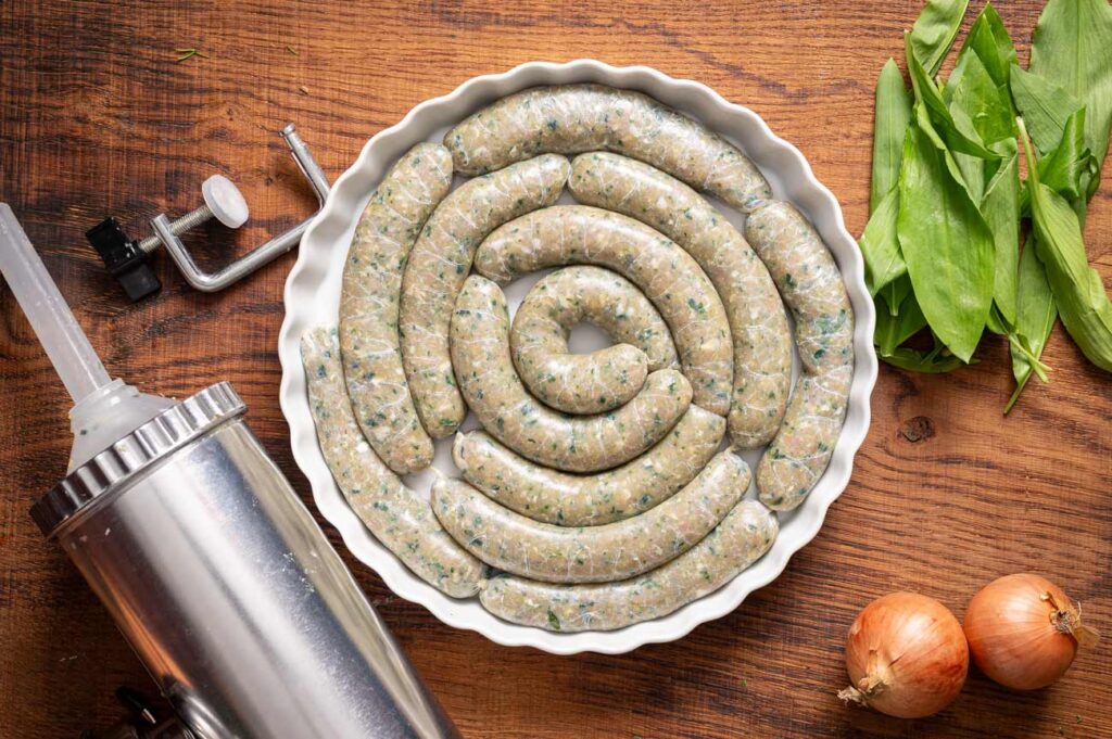 Saftige Bärlauch Bratwurst aus Hähnchenfleisch, frisch gegrillt mit goldbrauner Kruste und feiner Würze, serviert mit Bärlauch und Beilagen.