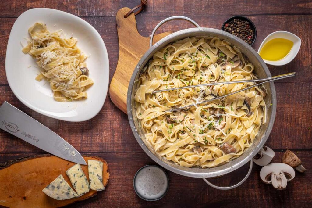 Ein Teller Tagliatelle mit cremiger Gorgonzola Soße, gebratenen Champignons und einem Hauch Trüffelöl, serviert mit geriebenem Parmesan.