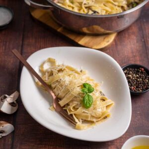 Tagliatelle werden in Gorgonzola Käsesoße geschwenkt und mit Trüffelöl verfeinert, bevor sie auf einem Teller angerichtet werden.