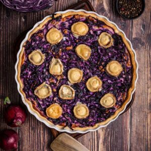 Frisch gebackene Rotkohl Quiche mit Ziegenkäse und Walnüssen auf einem Holzbrett