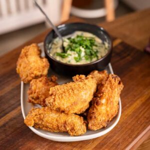 Knusprige Buttermilk Fried Chicken Wings auf einem Teller, serviert mit frischer Bärlauch-Mayonnaise als Dip