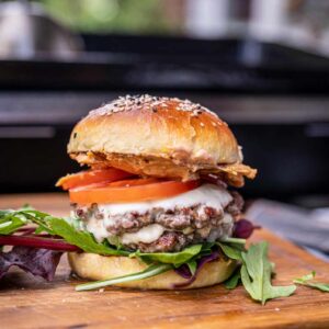 Frisch belegter Burger mit hausgemachter Baconnaise, Rindfleisch-Patty, Tomate, Salat und Cheddar im gerösteten Bun