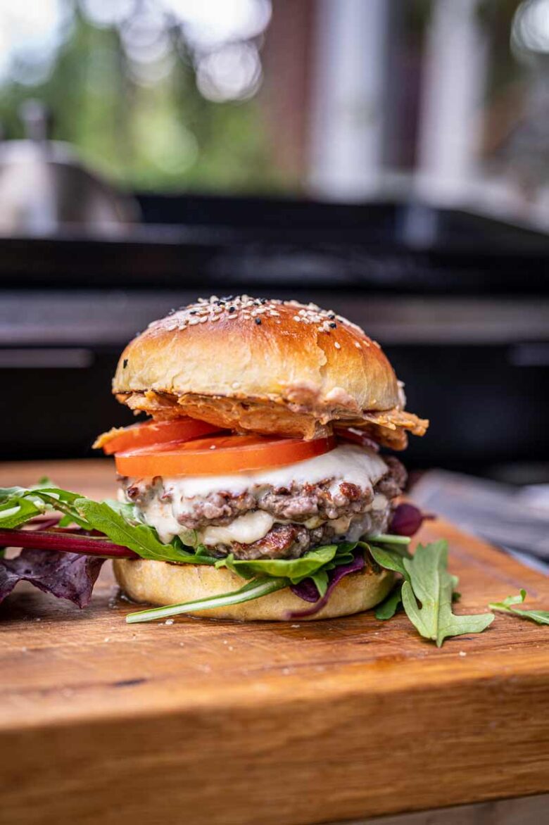 Frisch belegter Burger mit hausgemachter Baconnaise, Rindfleisch-Patty, Tomate, Salat und Cheddar im gerösteten Bun
