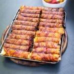 Fertig gegrillte Shotgun Shells mit glänzender BBQ-Glasur, angerichtet auf dem Holzbrett mit Messer