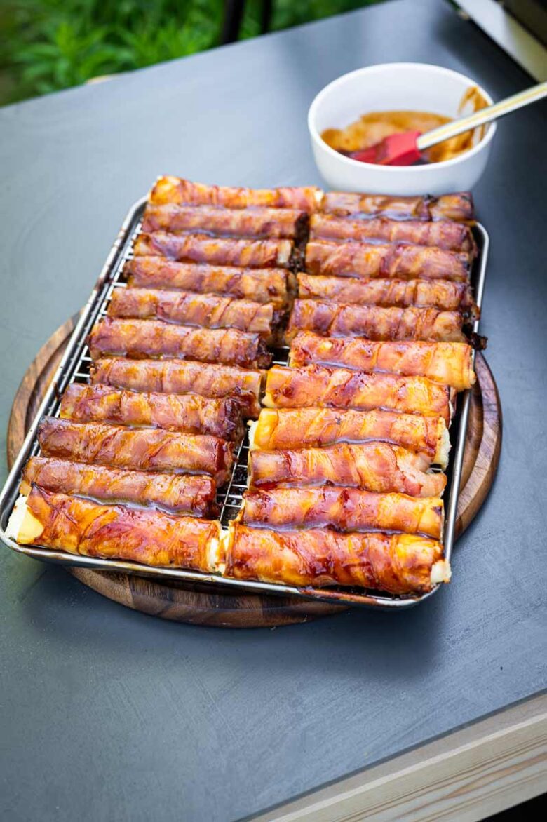 Fertig gegrillte Shotgun Shells mit glänzender BBQ-Glasur, angerichtet auf dem Holzbrett mit Messer