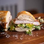 Frisch belegtes Chicken Sandwich mit Caesar Dressing, Römersalat und Parmesan auf knusprigem Sandwich Baguette