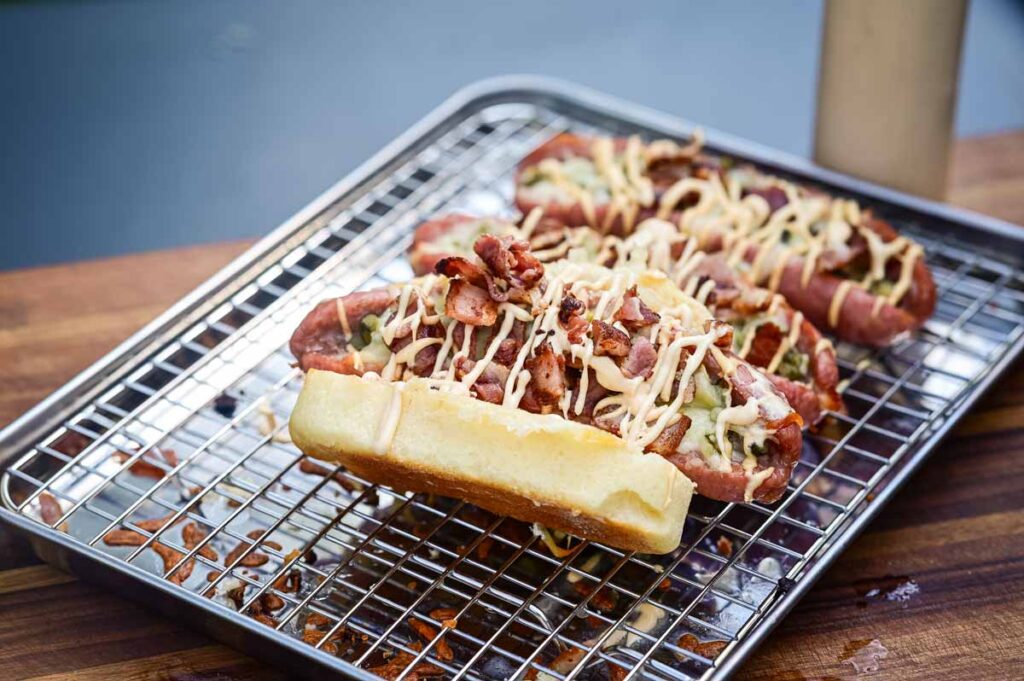 Fertige Cheeseburger Bratwurst mit geschmolzenem Käse, knusprigem Bacon und Burger Soße serviert im Hot Dog Bun