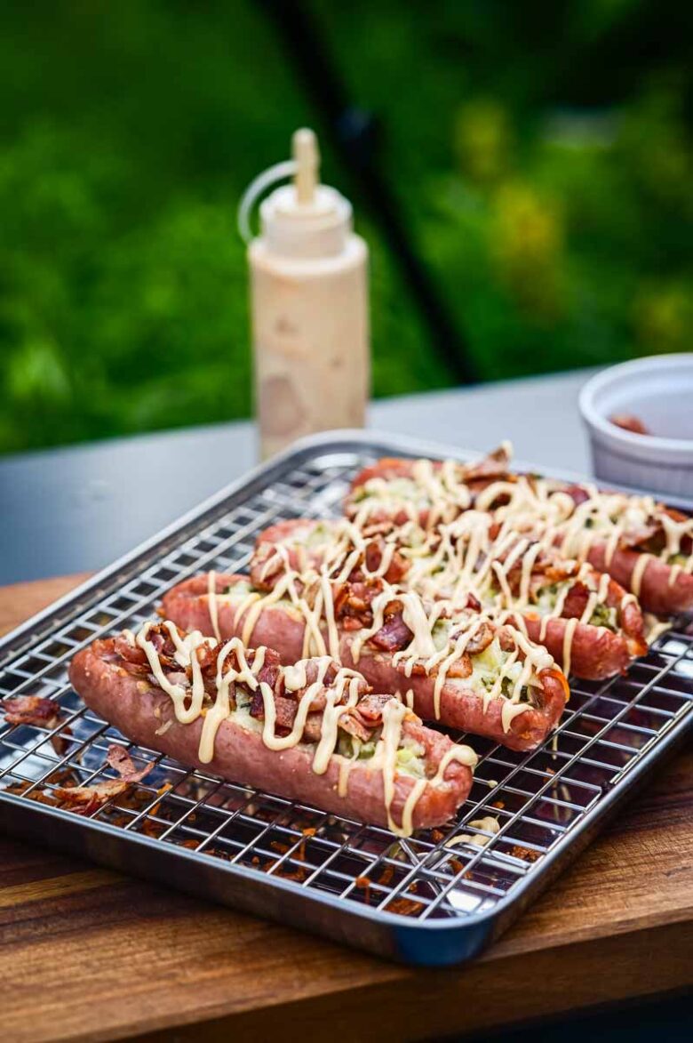 Detailaufnahme vom Bacon-Topping auf der Cheeseburger Bratwurst mit cremiger Burger Soße und geschmolzenem Käse
