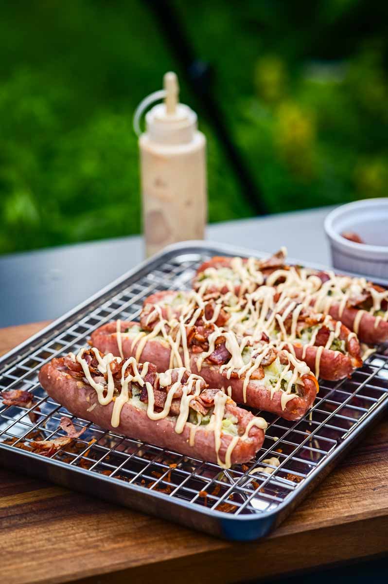 Detailaufnahme vom Bacon-Topping auf der Cheeseburger Bratwurst mit cremiger Burger Soße und geschmolzenem Käse