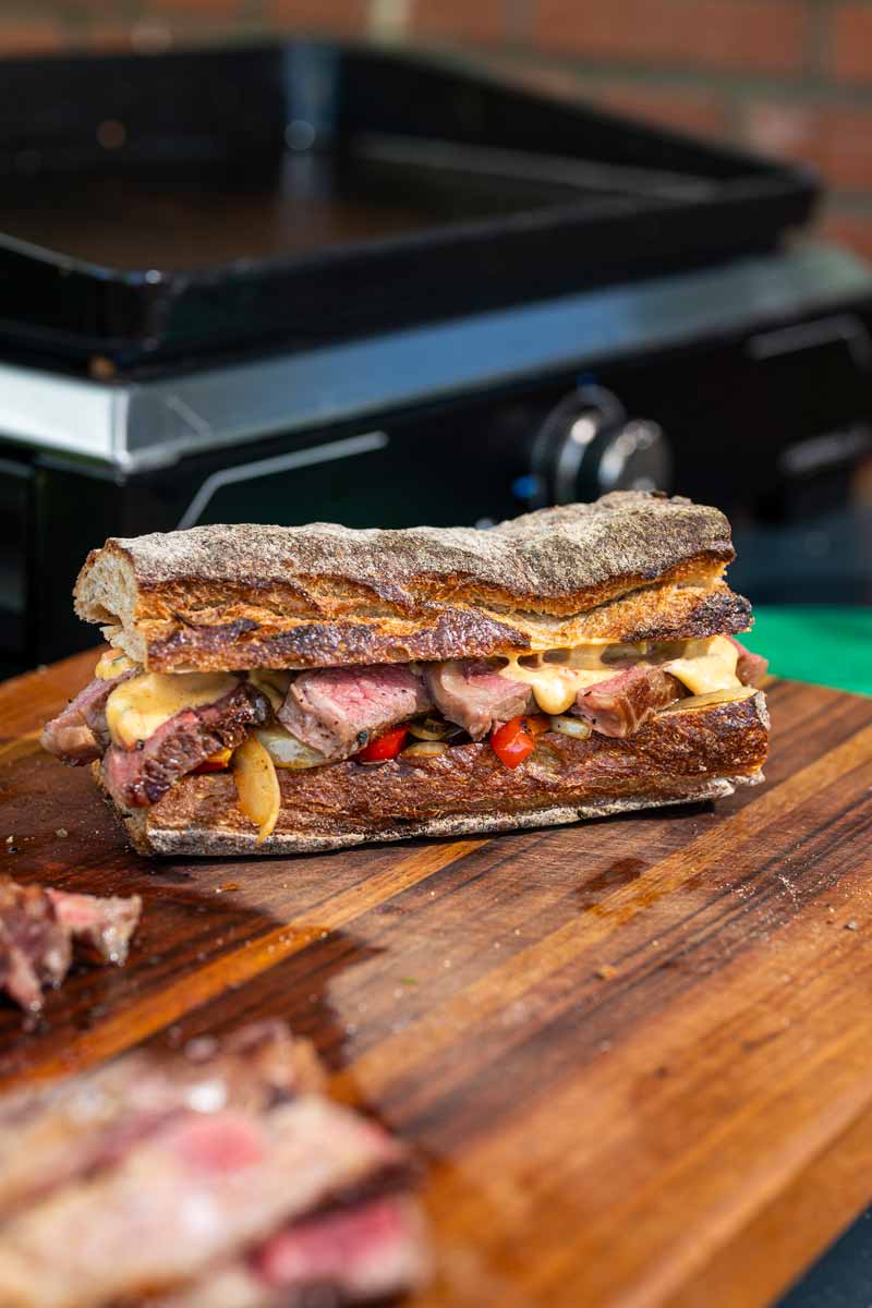 Frisch belegtes Steak Sandwich mit Ribeye, Paprika, Zwiebeln und würziger Chili Cheese Sauce