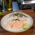Gegrillter Lachs mit knuspriger Haut auf der Plancha, frisch gewürzt mit Salz und Pfeffer