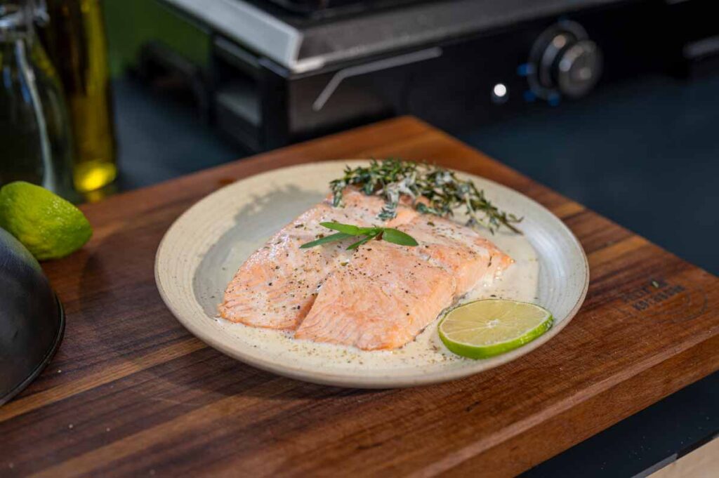 Nahaufnahme von gegrilltem Lachs mit knuspriger Haut und cremiger Limetten-Weißwein-Soße