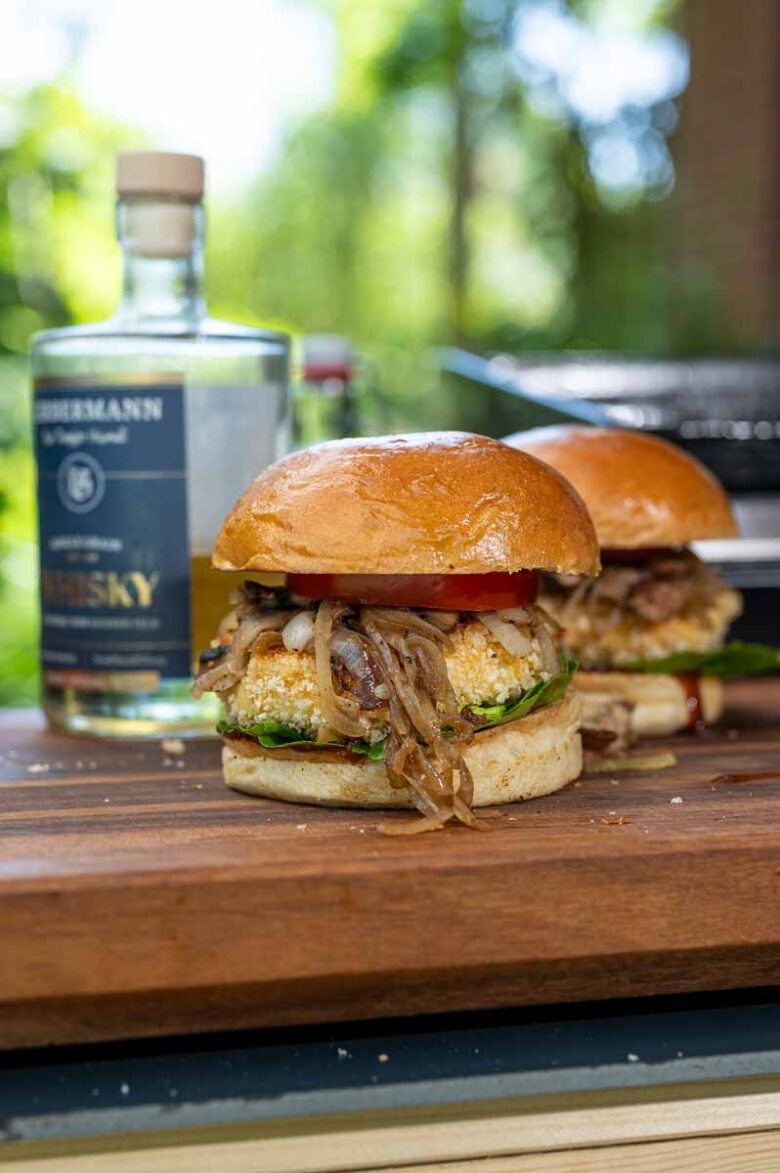 Knusprig panierter Grillkäse im vegetarischen Burger mit geschmolzenem Kern und frischem Gemüse.