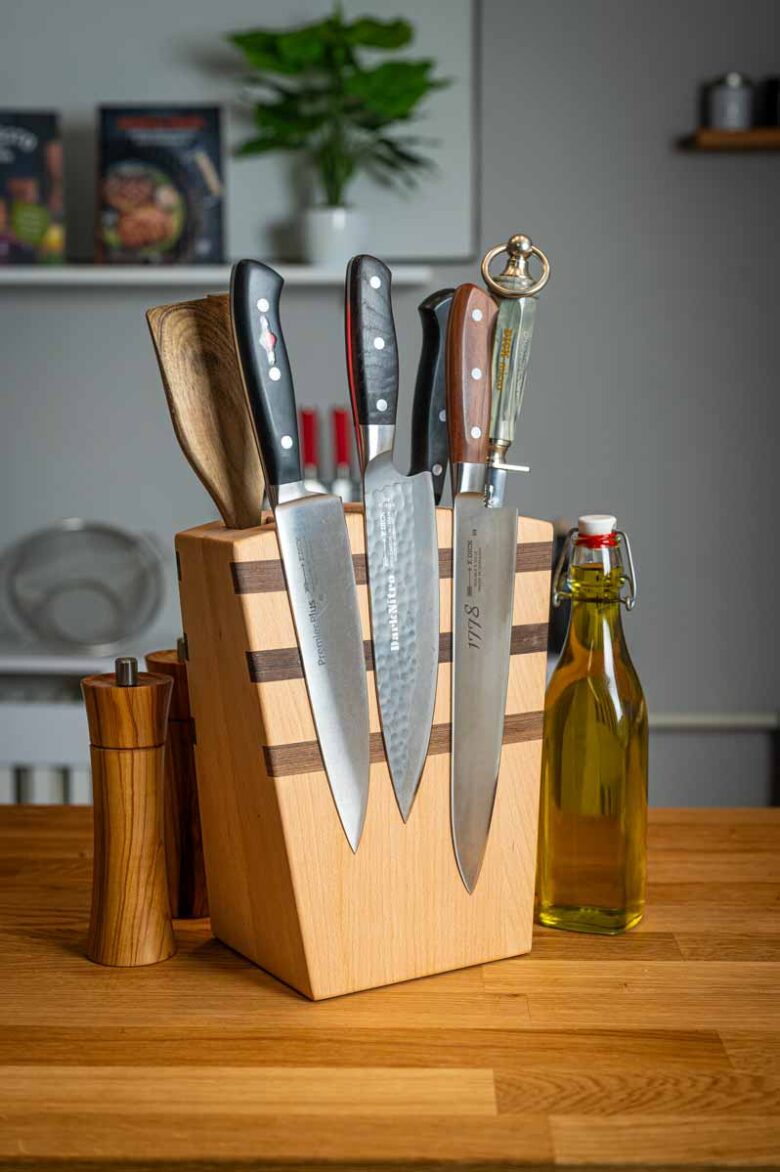 Verschiedene Küchenutensilien auf einem Holztisch, darunter Schneebesen, Pfannenwender, Reibe, Küchenzange und Silikonspatel – perfekt für Hobbyköche