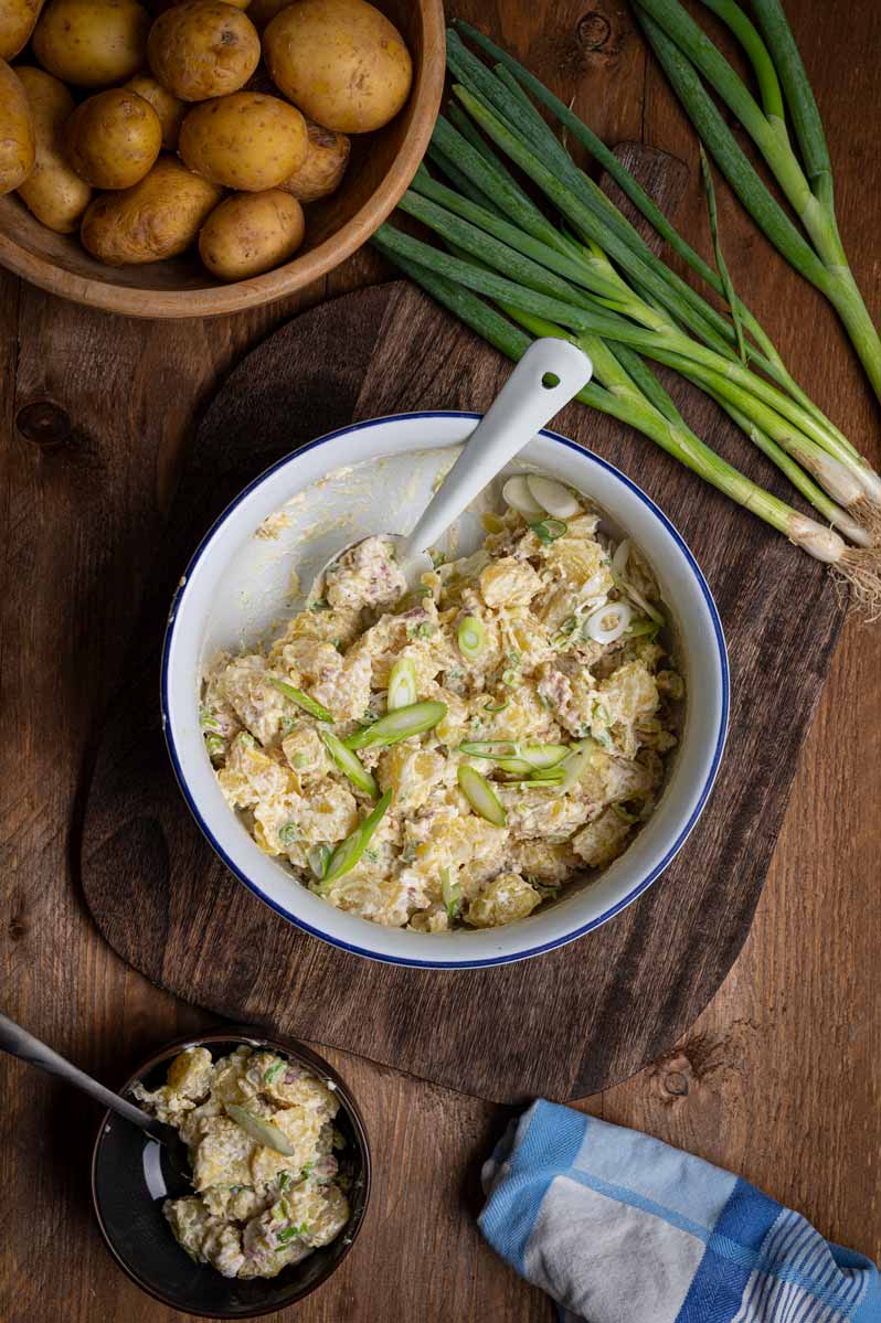 Nahaufnahme vom cremigen Baked Potato Salat mit knusprigem Bacon, Frühlingszwiebeln und cremigem Dressing in einer weißen Schüssel