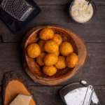 Knusprige Kartoffel-Käse-Bällchen mit Parmesan, goldbraun frittiert und als Snack angerichtet