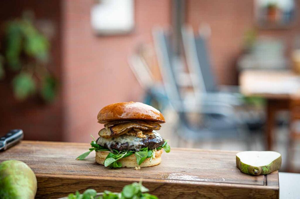 Saftiger Wagyu Burger mit geschmolzenem Blauschimmelkäse, Birnenscheiben und karamellisierten Walnüssen