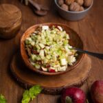 Nahaufnahme einer Gabel mit Apfel Sellerie Salat, knackigen Selleriescheiben, Apfelstücken und Walnüssen