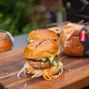 Fertiger Banh Mi Burger mit saftigem Patty, eingelegtem Gemüse, Gurken und frischen Kräutern, servierfertig auf einem Teller