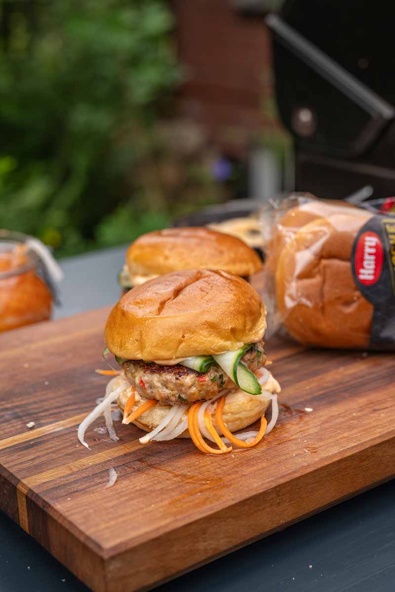 Fertiger Banh Mi Burger mit saftigem Patty, eingelegtem Gemüse, Gurken und frischen Kräutern, servierfertig auf einem Teller