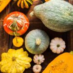 Verschiedene Kürbissorten wie Hokkaido, Butternut und Bischofsmütze liegen auf einem rustikalen Holztisch – perfekte Zutaten für herbstliche Kürbisrezepte.