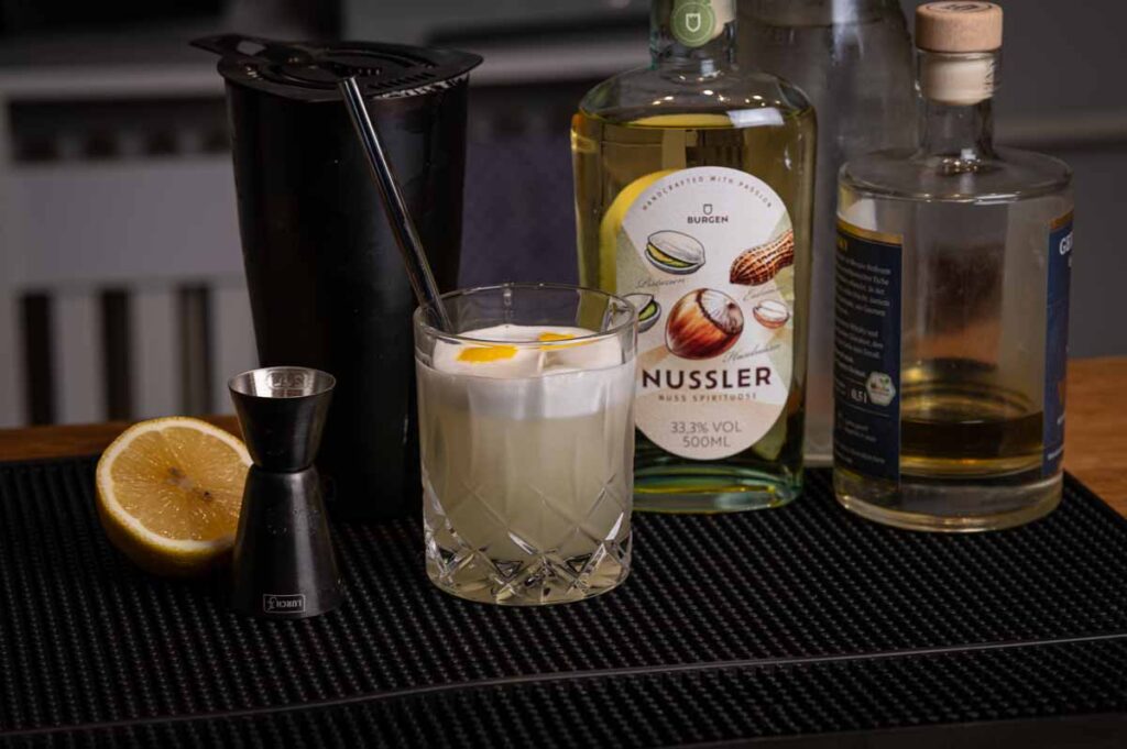 Glas Nussler Sour mit Zitronenzeste auf Eis serviert