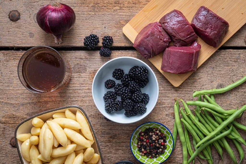 Die Zutaten für den Rehrücken mit fruchtiger Brombeersoße, grünen Bohnen und knusprigen Schupfnudeln auf einem Teller