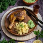 Serviertes Gericht mit knusprigem Hähnchen, cremigem Grünkohl Hummus und goldenem Couscous auf einem Teller – orientalisches Winterrezept.