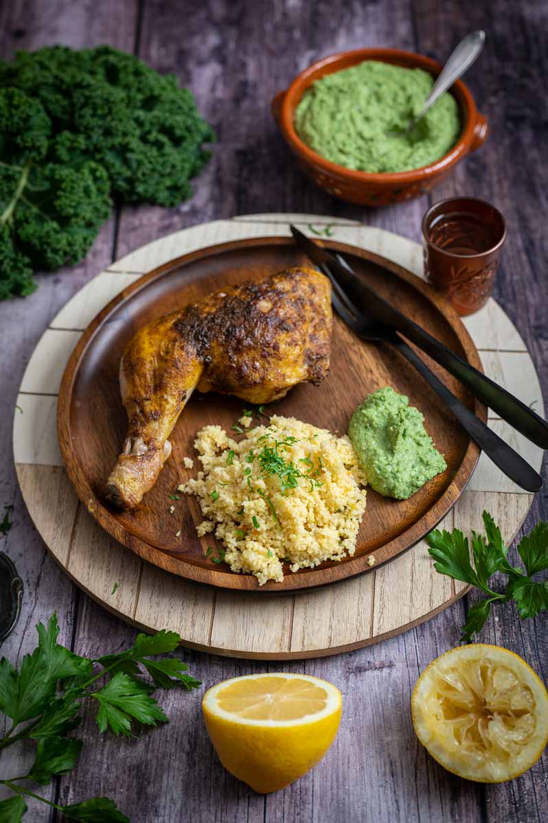 Serviertes Gericht mit knusprigem Hähnchen, cremigem Grünkohl Hummus und goldenem Couscous auf einem Teller – orientalisches Winterrezept.