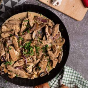 Fertig serviertes Pilzgeschnetzeltes mit cremiger Soße und lockerem Basmati-Reis auf einem Teller.