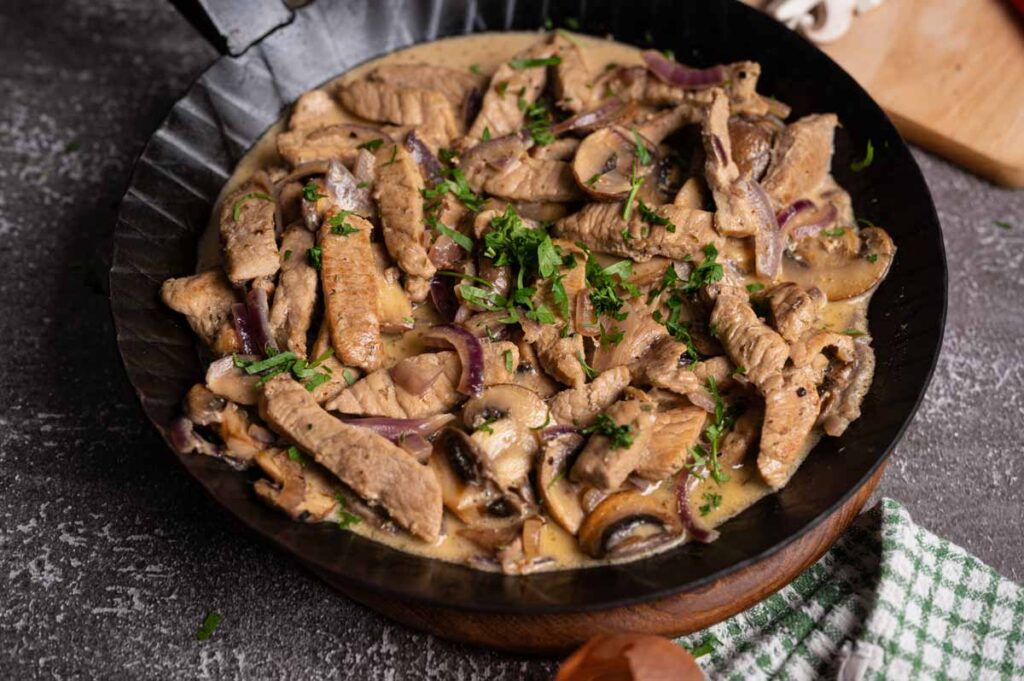 Zartes Geschnetzeltes in Pilzrahmsoße, frisch angerichtet und mit Kräutern garniert.