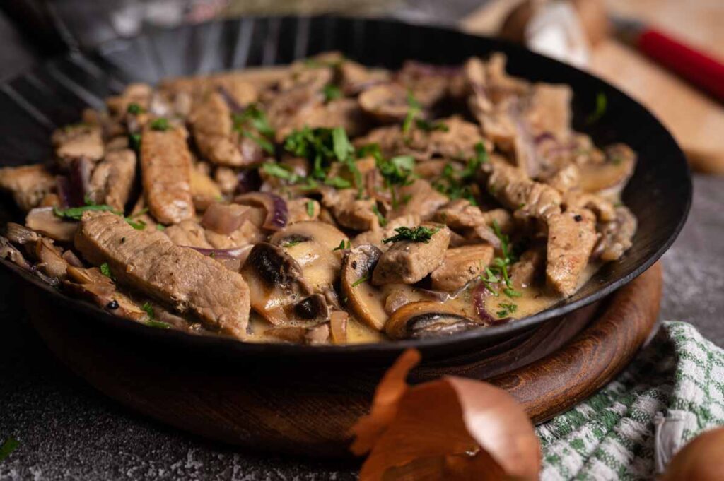 Cremiges Pilzgeschnetzeltes als fertige Mahlzeit, serviert mit Reis und leicht gebräunten Champignons.