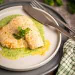 Samtige grüne Kräuter Velouté elegant auf einem Teller mit Wolfsbarschfilet angerichtet