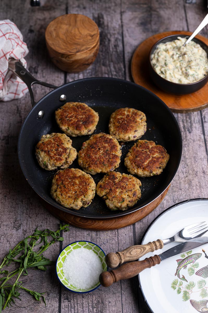 Goldbraun gebratene Fischfrikadellen aus Seelachsfilet in der Pfanne