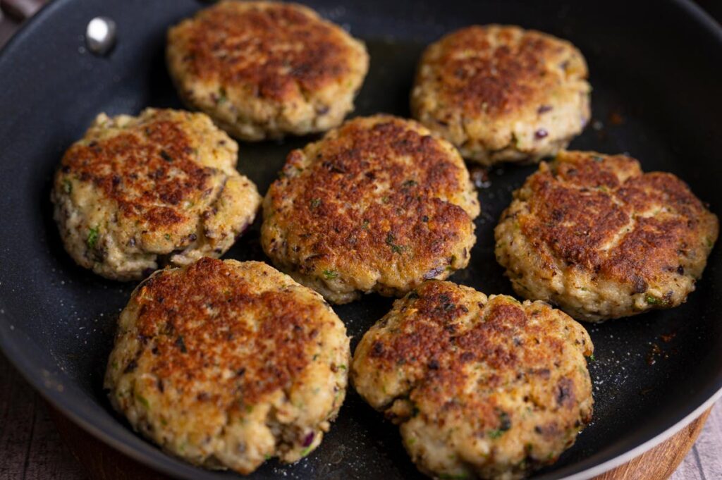 Goldbraun gebratene Fischfrikadellen aus Seelachsfilet in der Pfanne