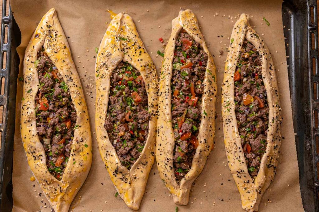 Goldbraune Pide mit Hackfleisch und Sesam auf einem Backblech