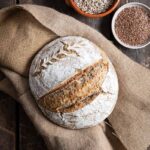 Selbst gebackenes Körner-Sauerteigbrot mit Dinkel, serviert mit Butter und Saaten